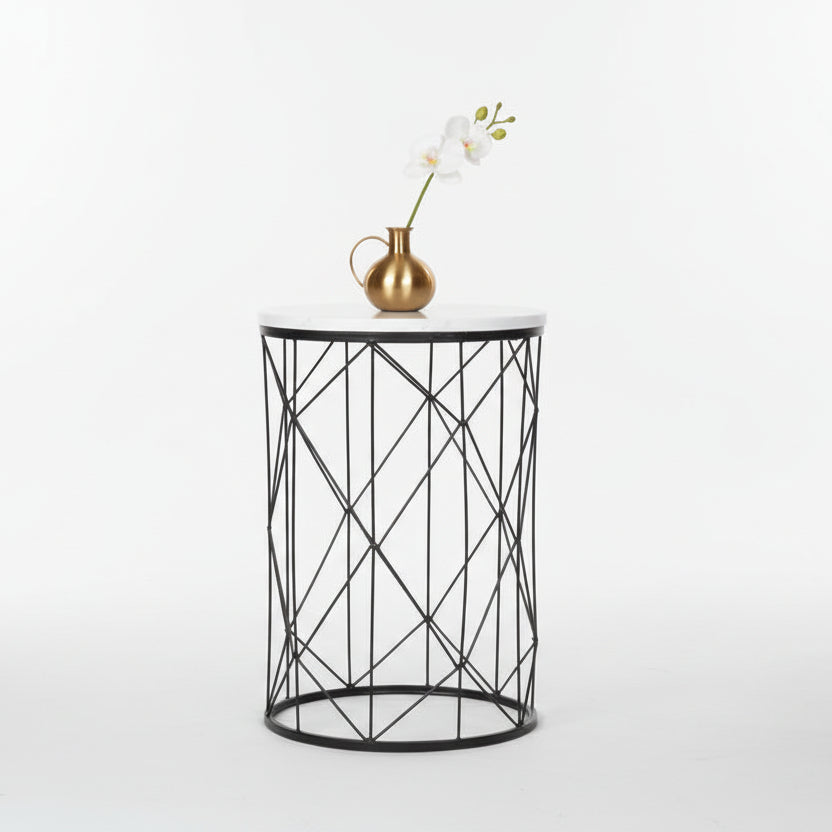 Black metal side table with white marble top against a blue wall with a green chair.