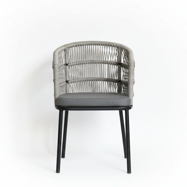 Chair with wicker backrest and gray cushion in a room with white walls and various materials.