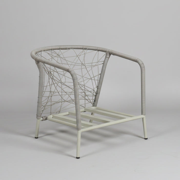 Wicker chair in a room with a white wall and concrete floor.