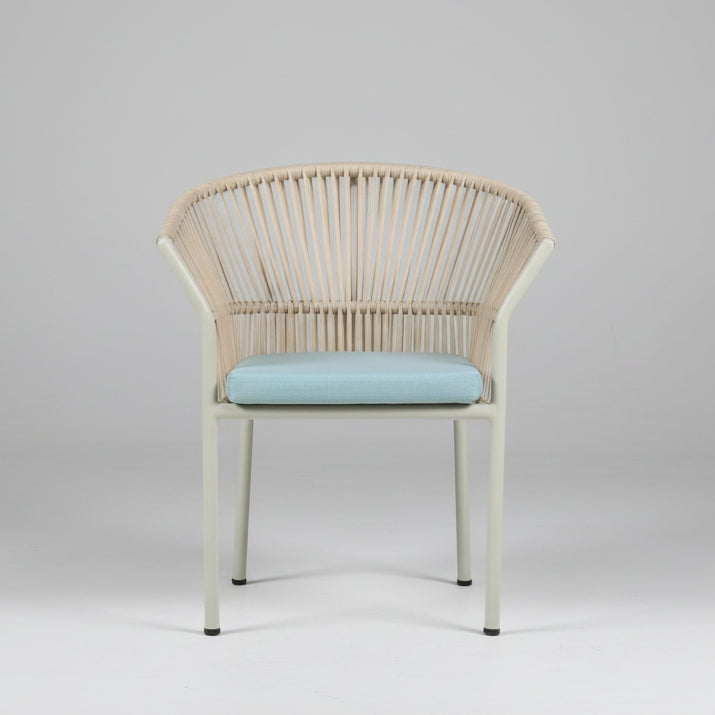 Wicker chair with a light blue cushion in a room with furniture and boxes.