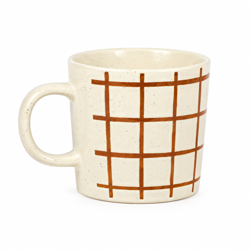 A speckled cream-colored ceramic mug with a brown grid pattern on the side, set against a neutral gray background.