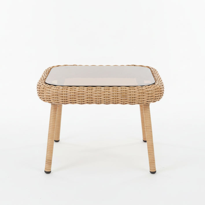 Wicker outdoor furniture set with green cushions on a stone patio.